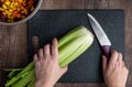 WomanÃ¢â¬â¢s hands, bunch of celery washed and ready to chop on a black cutting board with chef knife Royalty Free Stock Photo